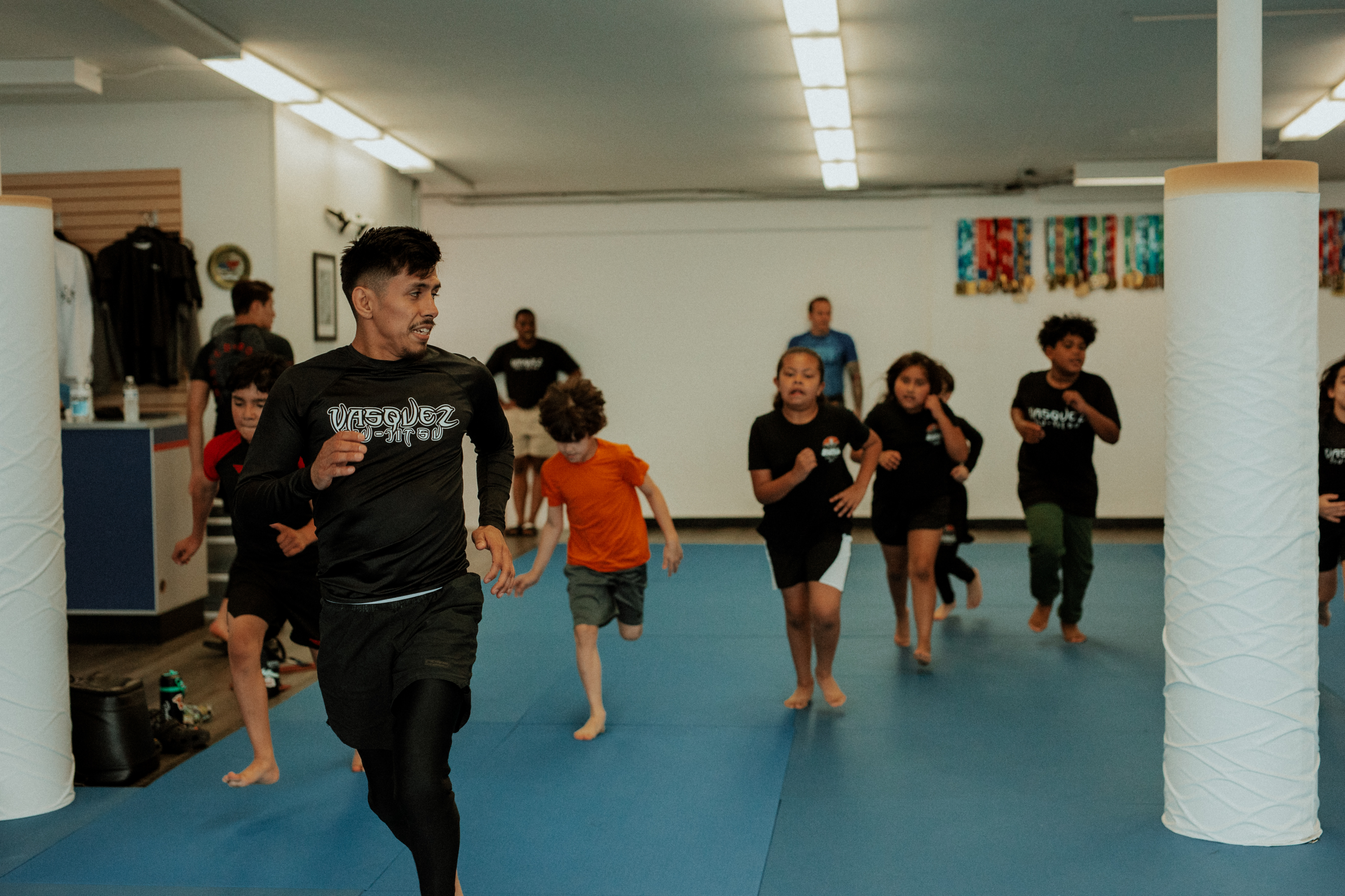 Coach leading kids through a warm-up at a Vasquez Jiu-Jitsu youth class